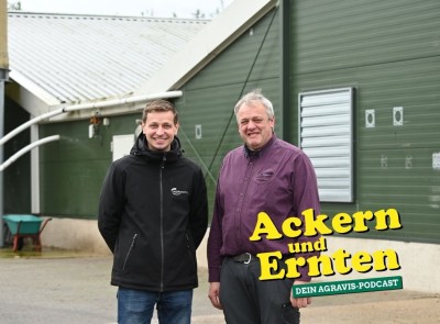 Zwei Personen stehen auf einem Betrieb und schauen in die Kamera.